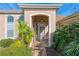 Covered front porch adorned with tropical plants, a tiled pathway, and an arched entrance at 12239 Se 92Nd Court Rd, Summerfield, FL 34491