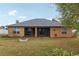 Back view of home with the patio, a fire pit and a lush green lawn at 13101 Biscayne Dr, Grand Island, FL 32735