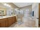 Bathroom featuring double sinks, tiled floors, glass shower, and large soaking tub at 13101 Biscayne Dr, Grand Island, FL 32735