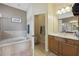 Bright bathroom featuring a tiled tub, toilet room, double sinks, and vanity at 13101 Biscayne Dr, Grand Island, FL 32735