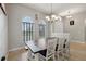 Elegant dining area with a large wooden table, white chairs, modern chandelier, and arched windows at 13101 Biscayne Dr, Grand Island, FL 32735