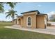 Stylish single-story home featuring a tan exterior, arched windows, lush lawn, and a palm tree at 13101 Biscayne Dr, Grand Island, FL 32735