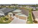 Aerial view featuring a well-manicured lawn, complemented by a beautifully landscaped garden and a spacious three-car garage at 1581 Rowell St, The Villages, FL 34762