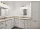 Dual vanity bathroom with framed mirrors, granite countertops, and white cabinetry providing a clean and modern aesthetic at 1581 Rowell St, The Villages, FL 34762