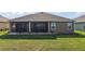 The exterior back of the home shows the screen enclosed lanai and well maintained lawn at 1581 Rowell St, The Villages, FL 34762