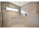 Modern shower with gray tile, frosted window, corner seat, handheld shower head and safety bar at 1581 Rowell St, The Villages, FL 34762