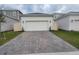 Two car garage with a paved driveway and manicured lawn at 1723 Happiness Row, Kissimmee, FL 34744