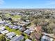 An aerial view of a residential neighborhood featuring a golf course and pond, showcasing community layout under a clear, blue sky at 1727 Hilton Head Blvd, Lady Lake, FL 32159