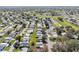 Aerial view shows a community adjacent to a golf course and a pond, all set against a backdrop of lush green spaces at 1727 Hilton Head Blvd, Lady Lake, FL 32159