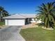 Charming single-story home with a well-manicured lawn, brick driveway, attached garage, and a large palm tree at 17490 Se 110Th Ter, Summerfield, FL 34491