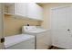 A well-lit laundry room equipped with modern washer and dryer, overhead cabinets and extra freezer space at 17490 Se 110Th Ter, Summerfield, FL 34491
