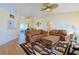 Bright living room with hardwood floors, comfortable sofas, ceiling fan, and view into the dining area and lanai at 17490 Se 110Th Ter, Summerfield, FL 34491