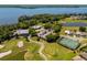 Expansive aerial view showcasing the golf course, tennis courts, clubhouse, and residential area near the lake at 17648 Live Oak Dr, Tavares, FL 32778