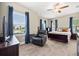 Comfortable bedroom with wood look floors, ceiling fan, and a large window overlooking the neighborhood at 17648 Live Oak Dr, Tavares, FL 32778