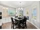 Bright dining area with a dark wood table, a chandelier, and a view of the backyard through the windows at 17648 Live Oak Dr, Tavares, FL 32778