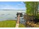 Aerial view of a long dock leading to a covered boat house with serene lake backdrop at 17648 Live Oak Dr, Tavares, FL 32778
