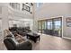 Spacious living room featuring high ceilings, a leather sofa, and sliding doors to the patio overlooking the lake at 17648 Live Oak Dr, Tavares, FL 32778
