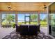 Covered patio with an outdoor dining table and chairs overlooking a serene lake and lush greenery at 17648 Live Oak Dr, Tavares, FL 32778