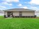 A green backyard with a covered patio is lined with shrubbery and has space for chairs at 17728 Se 115Th Ct, Summerfield, FL 34491