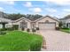 Well-maintained home featuring manicured landscaping, a brick driveway, and a welcoming facade at 17728 Se 115Th Ct, Summerfield, FL 34491