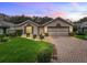 Charming single-story home with manicured lawn, beautiful landscaping, and a brick-paved driveway at 17728 Se 115Th Ct, Summerfield, FL 34491