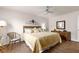 Cozy bedroom with wood-look floors, a ceiling fan, wicker chair, and decorative headboard at 2136 Kerwood Loop, The Villages, FL 32162