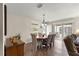 This dining room has wood-look floors, a round table, a vintage light fixture, and a sliding glass door to the patio at 2136 Kerwood Loop, The Villages, FL 32162