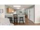 This kitchen has a breakfast bar with seating, light wood cabinets, white appliances, and a dining area at 2136 Kerwood Loop, The Villages, FL 32162