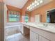 Bright bathroom with double vanity, separate tub, and serene backyard views at 2185 Caxton Ave, Clermont, FL 34711