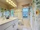 Bright bathroom with a white vanity, sunflower shower curtain, and a window with a decorative valance at 2185 Caxton Ave, Clermont, FL 34711
