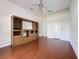 A spacious living room features hardwood floors, bright white walls, a ceiling fan and a large built-in wall unit at 2185 Caxton Ave, Clermont, FL 34711
