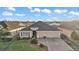Aerial view of a well-maintained home with a gray roof, three car garage, and a beautifully landscaped front yard at 2212 Bachman Path, The Villages, FL 32162