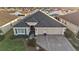 Aerial view of a well-maintained home with a gray roof, three car garage, and a beautifully landscaped front yard at 2212 Bachman Path, The Villages, FL 32162