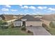 Aerial view of a well-maintained home with a gray roof, three car garage, and a beautifully landscaped front yard at 2212 Bachman Path, The Villages, FL 32162