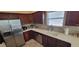 This kitchen includes stainless steel appliances, sleek countertops, dark cabinets, and tile backsplash at 2304 Jonesbury Run, The Villages, FL 32162