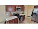 Modern kitchen with stainless steel appliances, dark wood cabinets, and bright countertops with tile backsplash at 2304 Jonesbury Run, The Villages, FL 32162