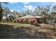Backyard view of house with a large yard with pink flowering bushes, and a wooden pergola at 2541 Lake Griffin Rd, Lady Lake, FL 32159