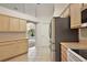 Kitchen features light wood cabinets, stainless steel refrigerator, and an opening to the living area at 2541 Lake Griffin Rd, Lady Lake, FL 32159