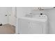 Well-lit laundry room with white washer, dryer, and built-in storage cabinets at 2606 Olivarez Way, The Villages, FL 32162
