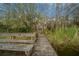 Wooden dock with bench leading to a lake, surrounded by trees and aquatic plants at 30713 George Dr, Tavares, FL 32778