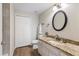 Well-lit bathroom featuring granite counters, wood flooring, a modern sink, and a black framed circular mirror at 3368 Parkchester Square Blvd # 104, Orlando, FL 32835