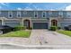 Exterior view of blue townhomes featuring a paver driveway, garages, manicured landscaping and red front doors at 384 Coral Beach Cir, Casselberry, FL 32707