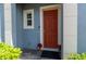 Close-up of a townhome's red front door framed by an archway, a small window, and manicured landscaping at 384 Coral Beach Cir, Casselberry, FL 32707