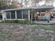 Cozy home featuring a sunroom, wooden porch, and lush landscaping at 43648 S Island Dr, Paisley, FL 32767