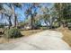 Long driveway with a view of a charming home shaded by mature trees at 6213 Highland Ave, Leesburg, FL 34748