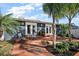 Covered patio with brick flooring, seating, and palm trees perfect for outdoor entertaining at 715 S Grandview St, Mount Dora, FL 32757