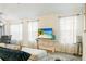 Bright living room has a flat screen tv, white sheer curtains, and neutral decor at 7163 Jerry Ave, The Villages, FL 34762