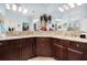 Bathroom vanity featuring a double sink, granite countertop, dark cabinets, and decorative accents at 8780 Bridgeport Bay Cir, Mount Dora, FL 32757