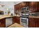 Modern kitchen featuring stainless steel appliances, granite countertops, and dark wood cabinets at 8780 Bridgeport Bay Cir, Mount Dora, FL 32757