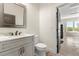 Bathroom featuring a marble countertop, light wood cabinets, and an open doorway to garage at 2600 Robie Ave, Mount Dora, FL 32757